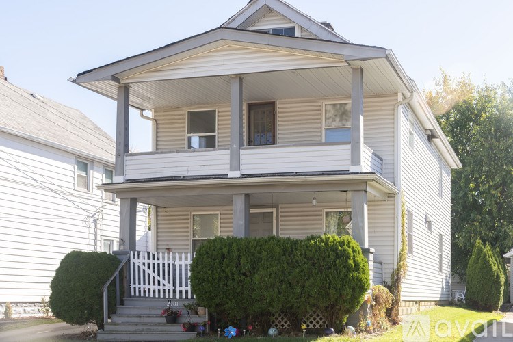 A two-story house with a white picket fence in front.
