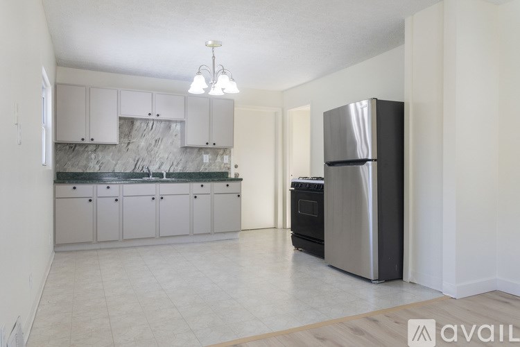 A kitchen with a refrigerator, cabinets, and a marble backsplash.