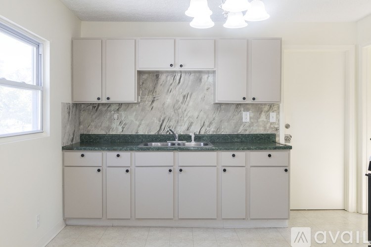 A kitchen with white cabinets and a marble countertop.