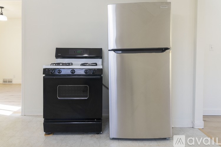 A black stove and a silver refrigerator in a room.