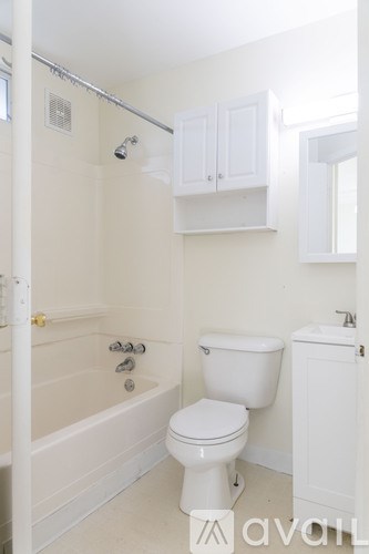A white toilet sits next to a white bathtub in a bathroom.