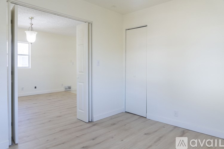 A room with a white door and wooden flooring.