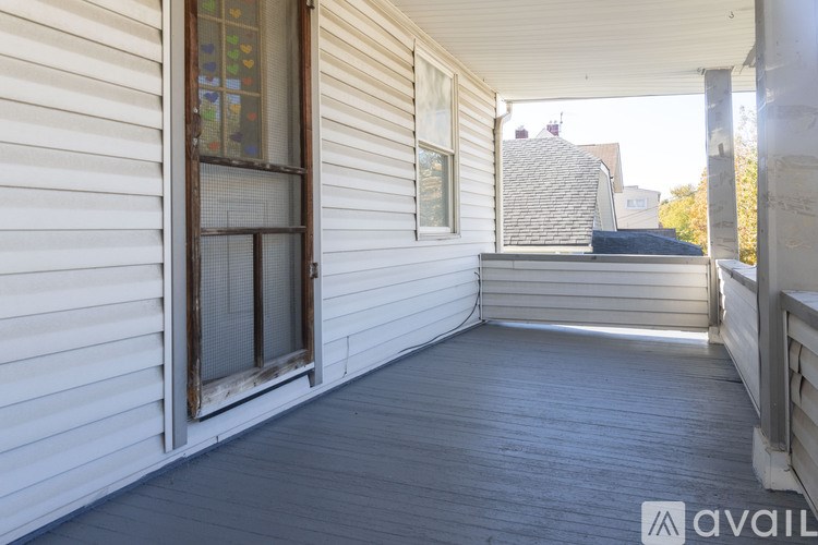 A porch with a wooden floor and a white wall.