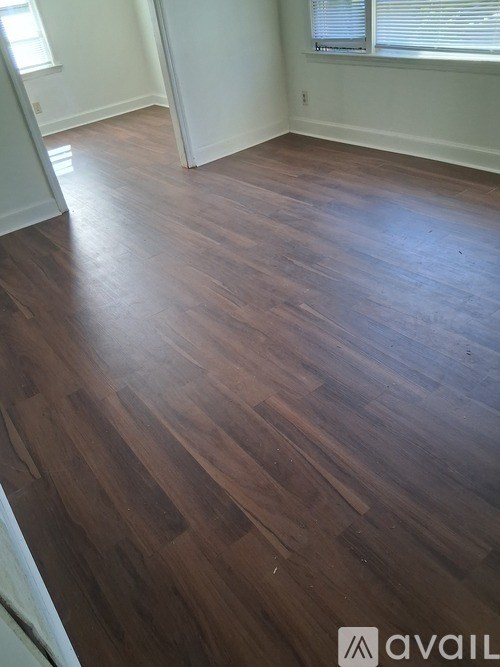 A room with wooden flooring and a window with blinds.