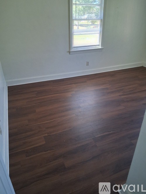 A room with a window and wooden flooring.