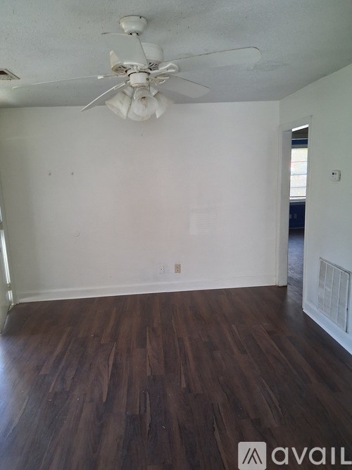 A room with a ceiling fan and wooden flooring.