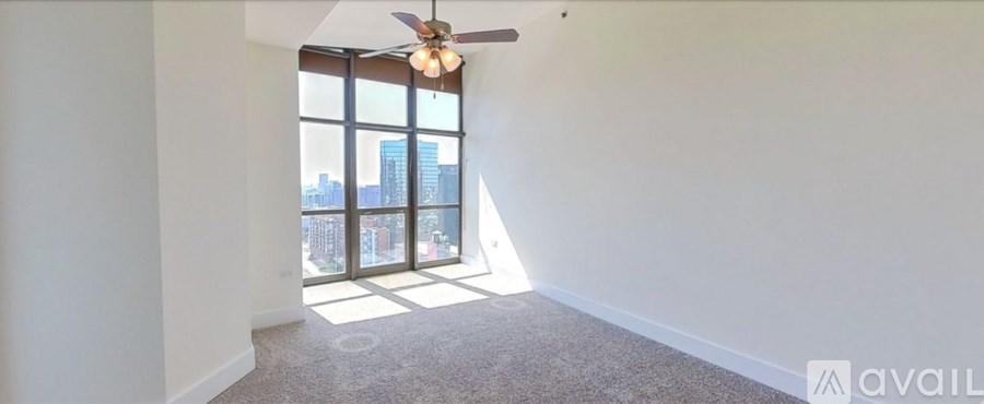 A room with a ceiling fan and a large window overlooking a cityscape.
