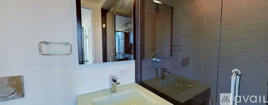 A bathroom with a sink, mirror, and glass shower door.