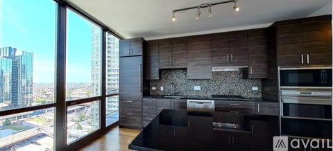 A modern kitchen with dark wood cabinets and a large window overlooking a cityscape.