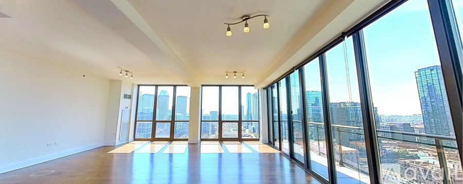 A large, empty room with a view of the cityscape outside the windows.