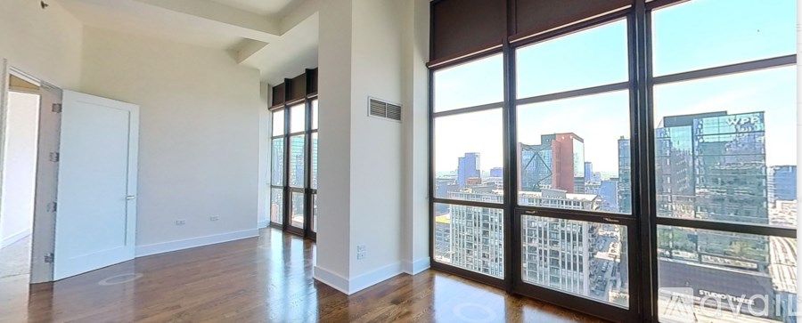 A large empty room with a view of the cityscape outside the windows.