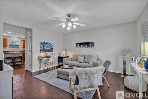 A living room with a grey couch and a white ceiling fan.