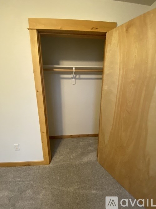 A room with a wooden door and a grey carpet.