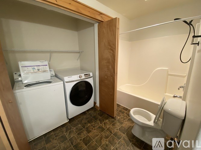 A small bathroom with a toilet, washing machine, and dryer.