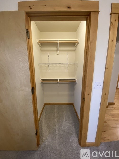 A small walk-in closet with a white door and shelves.