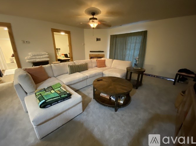 A living room with a white couch and a green throw pillow.