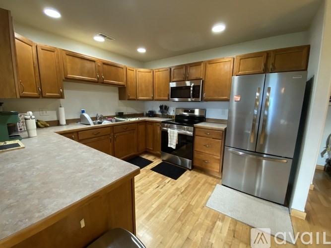 A kitchen with wooden cabinets and a stainless steel refrigerator.