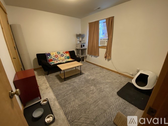 A room with a couch, a coffee table, and a robotic vacuum cleaner.