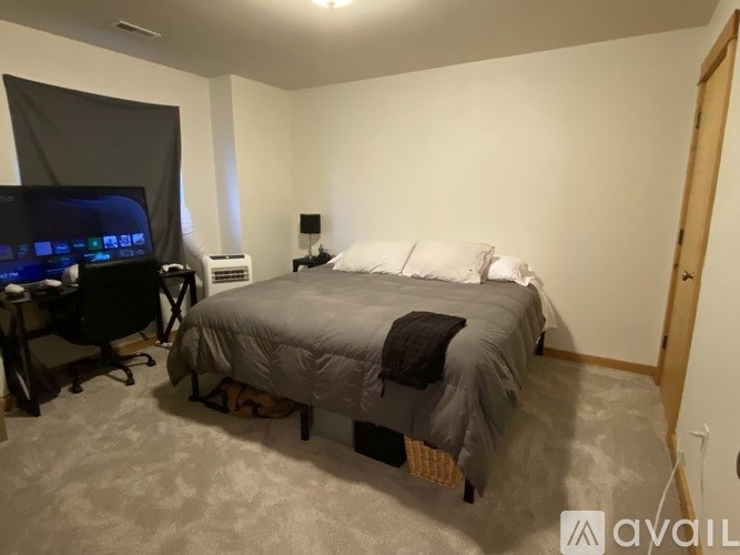 A bedroom with a bed, desk, and television.