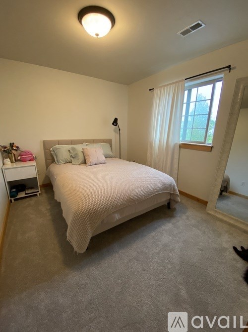 A bedroom with a bed, nightstand, and window.