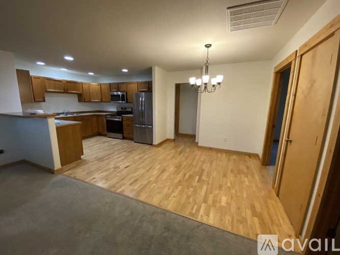 A spacious kitchen with wooden flooring and a chandelier.