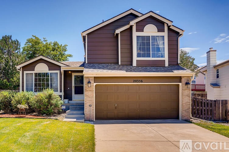 A house with brown siding and a garage door is for sale.