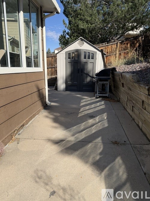 A small white shed sits in a backyard.