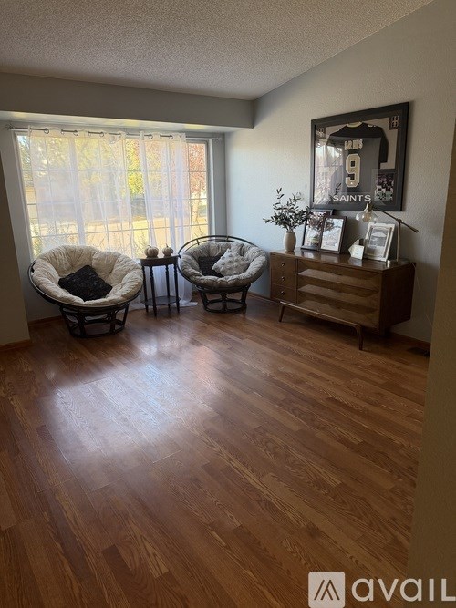 A room with wooden floors and two hanging chairs.