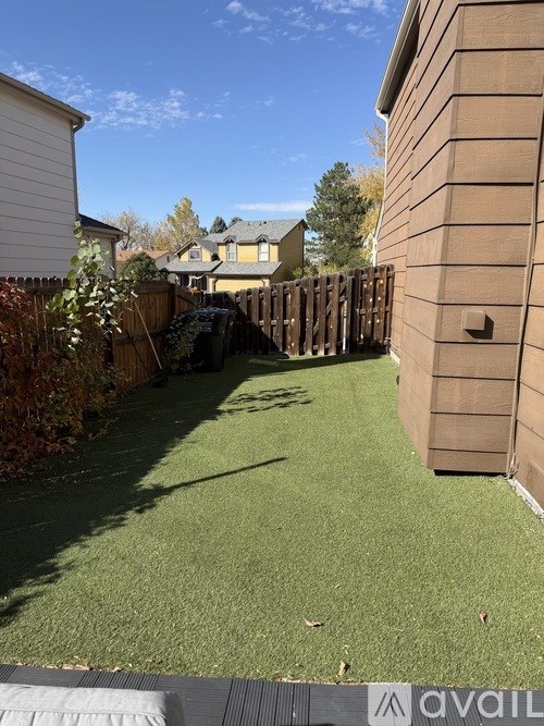 A backyard with a lawn and a wooden fence.