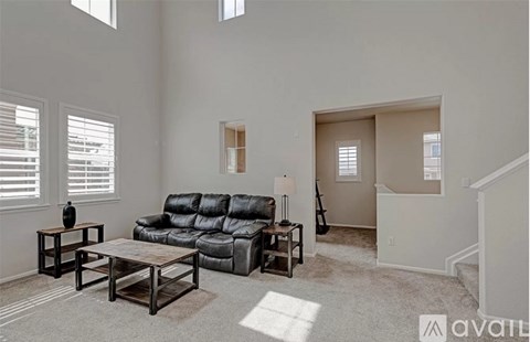 A living room with a black leather sofa and a wooden coffee table.