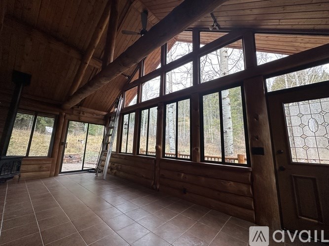 A large room with wooden walls and ceiling, tiled flooring, and a stained glass window.