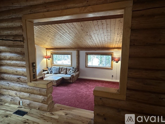 A wooden room with a window and a couch.