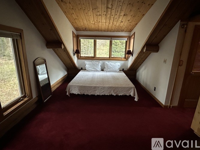 A bedroom with a bed, a window, and a mirror.