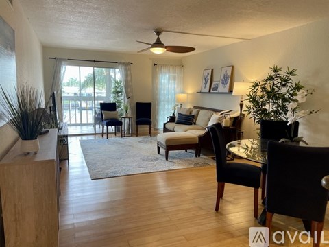 A living room with a ceiling fan and a dining table with chairs.