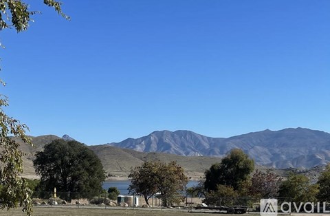 A landscape with a lake, trees and mountains in the background.