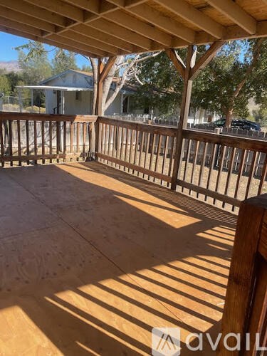 A wooden deck with a railing and a tree in the background.