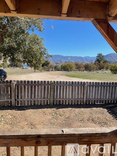 A wooden fence in front of a field with mountains in the distance.