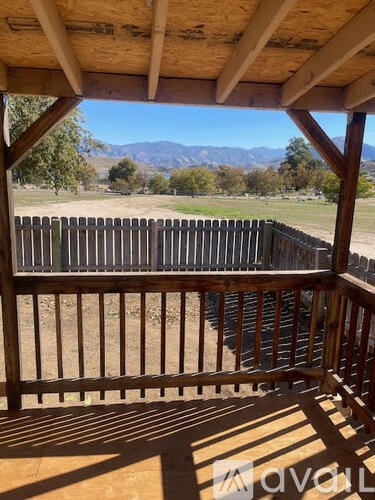 A wooden deck with a view of a fence and trees.