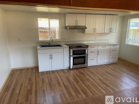 A kitchen with white cabinets and a wooden floor.