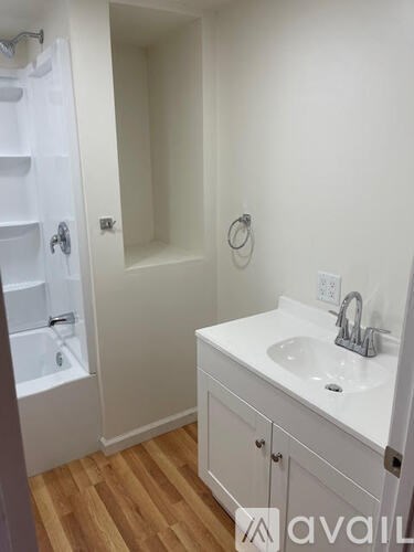 A white bathroom with a sink and a shower.
