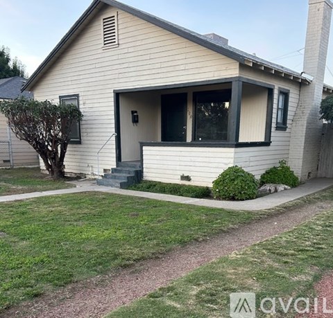 A small house with a front yard and a tree.