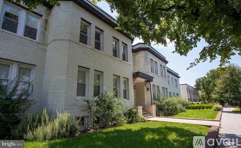 A white building with a tree in front of it.