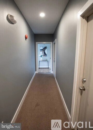 A hallway with a carpeted floor and a door on the right.