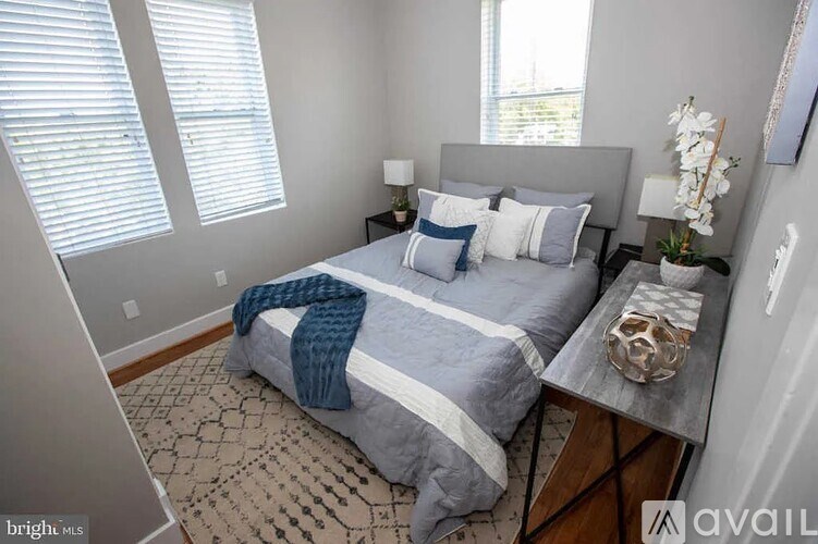 A bedroom with a bed, a nightstand, and a window with blinds.