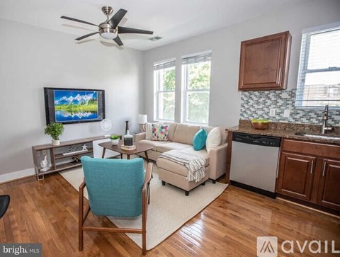 A living room with a blue chair and a television on the wall.