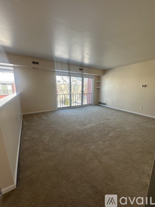 A carpeted room with a window and sliding glass door.