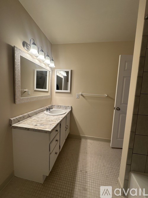 A bathroom with a marble countertop and two mirrors.