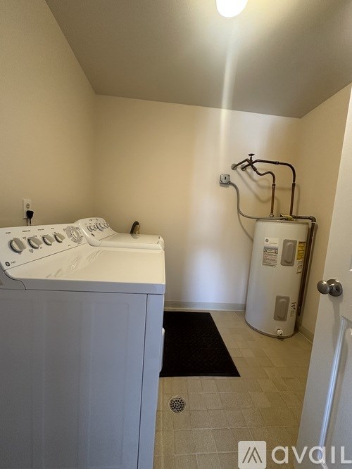 A small room with a washing machine and a water heater.