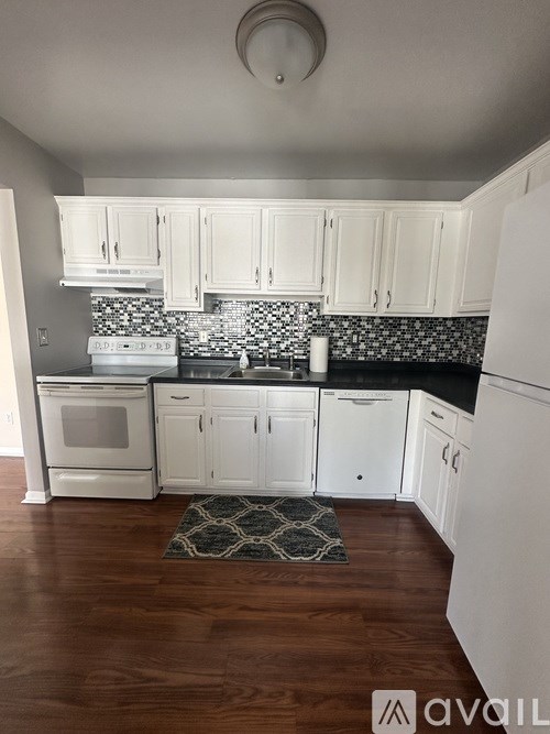 A kitchen with white cabinets and a black and white backsplash.