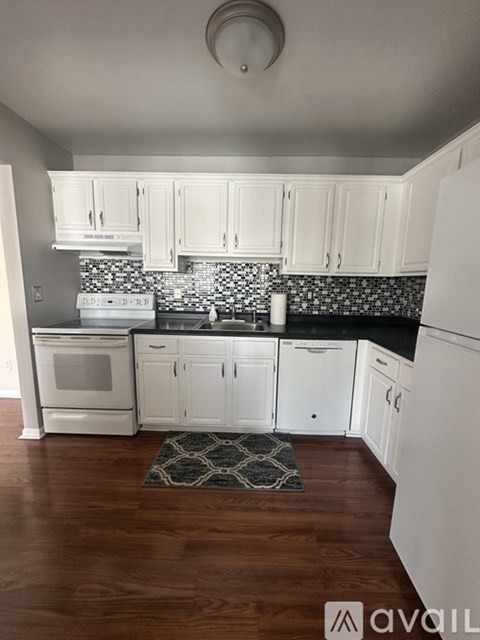 A kitchen with white cabinets and a black and white backsplash.